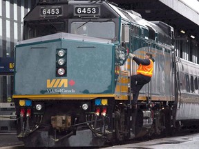 A Via Rail employee climbs aboard a locomotive at the train station in Ottawa on December 3, 2012. Via Rail, southern Ontario transit operator Metrolinx and BC Rapid Transit all say a strike at CP Rail would affect their operations.