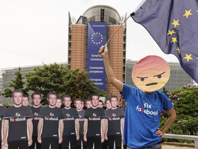 An Avaaz demonstrator waves the European flag as he stands next to life-sized Zuckerberg cutouts to protest against fake Facebook accounts spreading disinformation on the platform, near the EU Commission in Brussels, Tuesday, May 22, 2018. European Union lawmakers plan to press Facebook CEO Mark Zuckerberg on Tuesday about data protection standards at the internet giant at a hearing focused on a scandal over the alleged misuse of the personal information of millions of people.