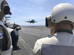 FILE - In this file photo dated  Tuesday, April 10, 2018, Observers watch from the deck of the U.S. aircraft carrier Theodore Roosevelt as a U.S. F-18 fighter jet lands, in international waters off South China Sea.  According to a report released Wednesday May 2, 2018, the Swedish arms watchdog Stockholm International Peace Research Institute, or SIPRI, said Global military spending rose to $1.739 trillion in 2017, a 1.1 percent increase on 2016, China continued its upward trend, and the United States' military spending remained constant for the second consecutive year.