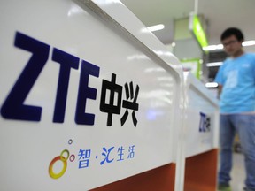 FILE - In this Oct. 8, 2012, file photo, a salesperson stands at counters selling mobile phones produced by ZTE Corp. at an appliance store in Wuhan in central China's Hubei province. President Donald Trump said Sunday, May 13, 2018, that he would help a Chinese telecommunications company get "back into business," saying too many jobs in China are stake after the U.S. government cut off access to its American suppliers. At issue is the Commerce Department's move last month to block the ZTE Corp., a major supplier of telecoms networks and smartphones based in southern China, from importing American components for seven years. (Chinatopix Via AP, File)