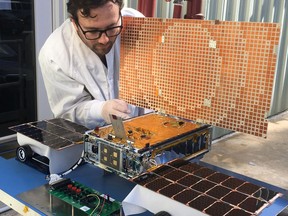 In this undated photo made available by NASA on March 29, 2018, engineer Joel Steinkraus uses sunlight to test the solar arrays on one of the Mars Cube One (MarCO) spacecraft at NASA's Jet Propulsion Laboratory in Pasadena, Calif. The MarCOs will be the first CubeSats - a kind of modular, mini-satellite - flown into deep space. They're designed to fly along behind NASA's InSight lander on its cruise to Mars. (NASA/JPL-Caltech via AP)