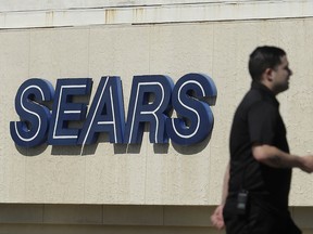 FILE- In this March 28, 2018, file photo, a man walks in front of a Sears sign in San Bruno, Calif. In a move announced Monday, May 14, Sears Holdings Corp. says a special committee of its board is starting a formal process to explore the sale of its Kenmore brand and related assets.