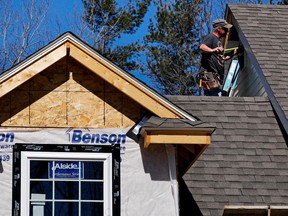 FILE- In this April 23, 2018, file photo, a worker installs vinyl siding on a new home in Auburn, N.H. On Tuesday, May 1, 2018, the Commerce Department reports on U.S. construction spending in March.