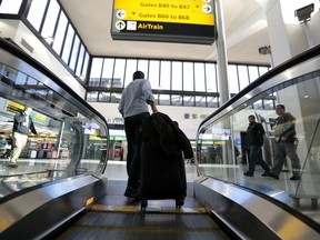 FILE- In this Nov. 22, 2016, file photo, a traveler pulls luggage off an escalator at Newark Liberty International Airport in Newark, N.J. If an airline forces a passenger off a flight for lack of space under federal rules the passenger is entitled to cash compensation, not just a voucher, and a seat on a later flight. Bumped passengers whose travel is delayed for at least an hour are entitled to up to $1,350 in compensation, with the amount based on the length of the delay and the one-way price of the ticket.