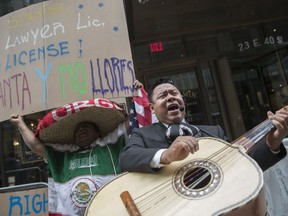 A demonstrator dances and sings along the Mariachi Tapatio de Alvaro Paulino band as they perform during a demonstration across the street from the building that once housed the office space of Aaron Schlossberg, Friday, May 18, 2018, in New York. Schlossberg, a lawyer who was caught on video ranting against Spanish-speaking restaurant workers has been kicked out of his office space and faces a complaint from two elected officials.