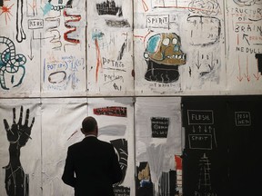 FILE- In this April 9, 2018 file photo, a man looks at the painting entitled 'Flesh and Spirit' by Jean-Michel Basquiat, in London, Prominent art collector Hubert Neumann has filed a lawsuit against Sotheby's auction house on Thursday, May 3, 2018, seeking to block the artist's daughter from selling the masterpiece that's worth an estimated $30 million.