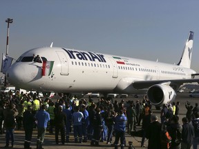 FILE - In this Jan. 12, 2017 file photo, the pilot of Iran Air's new Airbus plane waves a national flag after landing at Mehrabad International Airport in Tehran, Iran. European governments are scrambling for ways to save billions of dollars in trade that could collapse because of U.S. President Donald Trump's decision this week to re-impose sanctions.