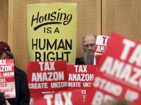 FILE - In this May 14, 2018 file photo, members of the public look on at a Seattle City Council before the council voted to approve a tax on large businesses such as Amazon and Starbucks to fight homelessness in Seattle. Amazon, Starbucks, Vulcan and a few dozen others have pledged more than $350,000 toward an effort to repeal Seattle's newly passed tax on large employers to combat homelessness.
