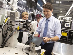Prime Minister Justin Trudeau, with Ontario Premier KathleenWynne, tries his hand at leather stitching with instructor Kyle McCaig during their visit to the TMMC Toyota Manufacturing facility in Cambridge, Ont. on Friday, May 4, 2018.