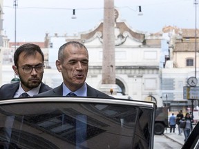 Premier-designate Carlo Cottarelli, center, gets in a car as he leaves his hotel, in Rome, Wednesday, May 30, 2018. Cottarelli has returned to the presidential palace for informal consultations amid continued market turmoil and uncertainty about the prospects of his proposed government.