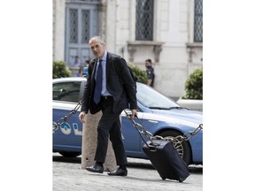 Economist Carlo Cottarelli arrives with his trolley bag at the Quirinale Presidential Palace to meet with Italian President Sergio Mattarella, in Rome, Monday, May 28, 2018. Italy's president Mattarella invited Cottarelli to the presidential palace on Monday amid speculation he would ask the former International Monetary Fund official to form a technical government following the collapse of what would have been Western Europe's first populist government.