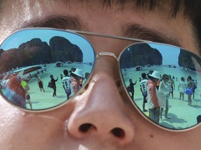 Tourists are reflected in sunglasses on Maya Bay on Phi Phi island in Krabi province, Thailand, Thursday, May 31, 2018. Maya Bay on Phi Phi Leh Island in the Andaman Sea will close to tourists for four months from Friday to give its coral reefs and sea life a chance to recover from an onslaught that began nearly two decades ago.