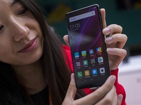 In this Feb. 26, 2018 file photo, a woman shows the new Xiaomi Mi MIX 2 during the Mobile World Congress wireless show, in Barcelona, Spain. Chinese smartphone maker Xiaomi filed documents Thursday, May 3, 2018, with Hong Kong's stock exchange operator for an initial public offering that could be the world's biggest share sale in years. Beijing-based Xiaomi is the world's fourth biggest smartphone maker by shipment volume, according to International Data Corp.