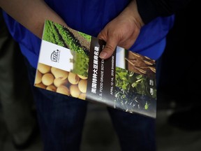 FILE - In this April 12, 2018 file photo, a Chinese visitor holds a U.S. soybean company's leaflet at the international soybean exhibition in Shanghai. With the threat of tariffs and counter-tariffs between Washington and Beijing looming, Chinese buyers are canceling orders for U.S. soybeans, a trend that could deal a blow to American farmers if it continues. At the same time, farmers in China are being encouraged to plant more soy, apparently to help make up for any shortfall from the United States.