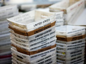 FILE- In this Dec. 14, 2017, file photo, boxes for sorted mail are stacked at the main post office in Omaha, Neb.  The U.S. Postal Service is reporting another quarterly loss after an unrelenting decline in mail volume and costs of its health care and pension obligations overcame strong gains in package deliveries.