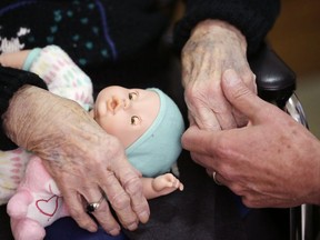 FILE - In this April 14, 2016, file photo, a son, at right, holds his mother's hand at her nursing home in Michigan. Most young adults haven't given much thought to their own needs as they get older, but a significant number are already providing long-term care for older loved ones, according to a new poll by the Associated Press-NORC Center for Public Affairs Research.