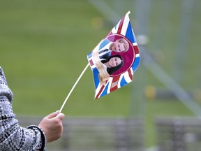 A tour guide leads her group of tourists using a flag with the faces of Britain's Prince Harry and his fiance Meghan Markle in Windsor, England, Wednesday, May 16, 2018. Preparations continue in Windsor ahead of the royal wedding of Britain's Prince Harry and Meghan Markle Saturday May 19.