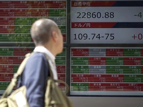 A man walks past an electronic stock board showing Japan's Nikkei 225 index at a securities firm in Tokyo Tuesday, May 15, 2018. Asian shares were mostly lower in muted trading Tuesday amid continuing uncertainty over trade tensions between China and the U.S.