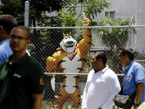 A statue of Kellogg's mascot, Tony the Tiger, stands behind the Kellogg's factory's fence, as workers gather outside in Maracay, Venezuela, Tuesday, May 15, 2018. Workers arriving Tuesday for the early shift were surprised to find a notice taped to an iron gate informing them that the company had been forced to shutter its operations.