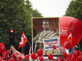 Protesters holding a placard with the face of President Macron reading "Macron, contemptuous of the Republic" take part of an afternoon march against President Emmanuel Macron's pro-business reforms and to demand more social justice in Paris, Sturday, May 26, 2018. Dozens of French labor unions, left-wing political parties and civil rights groups are calling for "floods of people".