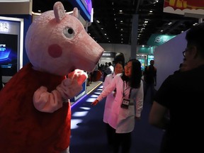 In this April 27, 2018 photo, a woman reacts to a Peppa Pig mascot during the Global Mobile Internet Conference (GMIC) in Beijing, China. The cherubic British cartoon character, Peppa Pig, has become an unlikely target of China's censors as online fans use her porcine likeness in sardonic memes and "gangster" catchphrases.