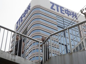 In this May 8, 2018, photo, Chinese men pass by a ZTE building in Beijing, China. President Donald Trump's weekend social media musings about China injected new uncertainty into the Washington's punishment of Chinese tech giant ZTE and planned trade talks between the two countries.