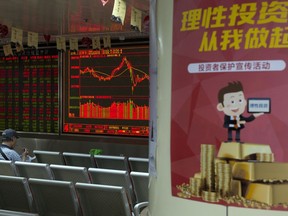 An investor eats his meal as he monitors stock prices near a poster which reads "Rational investing starts from me" at a brokerage in Beijing, China, Wednesday, May 9, 2018. Oil prices surged while Asian stock markets traded mixed after President Donald Trump announced the United States will withdraw from a 2015 nuclear accord with Iran and re-impose sanctions. Resulting rising oil prices would have a mixed impact across the region, driving prices higher for some countries that rely heavily on imports, such as Japan, while boosting revenues for exporters such as Indonesia.
