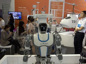 Visitors to the 21st China Beijing International High-tech Expo look at robots and helicopter drone displayed in Beijing, China, Thursday, May 17, 2018. The Trump administration has threatened to impose tariffs on up to $150 billion in Chinese imports to punish Beijing over trade practices requiring American companies to hand over technology in exchange for access to the Chinese market. China has counterpunched by targeting $50 billion in U.S. products.