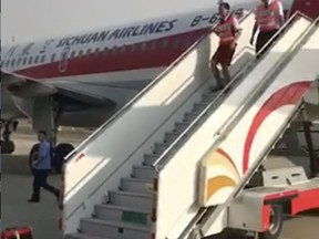 In this photo taken Monday, May 16, 2018, and released by a passenger who wishes to remain anonymous, ground crew are seen leaving the Sichuan Airline flight that made an emergency landing in Chengdu in southwestern China's Sichuan province. Chinese authorities and Airbus are investigating why the plane's cockpit windshield detached during a flight, forcing an emergency landing in an unusual mishap in one of the world's fastest growing aviation markets. (Passenger via AP)