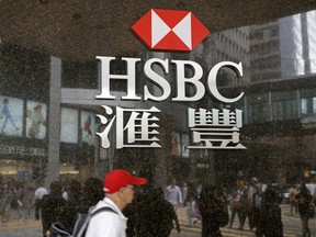 People walk past a branch of HSBC bank in Hong Kong, Friday, May 4, 2018. Global bank HSBC says pretax profits dipped in the latest quarter because of higher operating costs. The bank also said Friday that it's planning to buy back up to $2 billion in shares. It was its first quarterly earnings report under new Chief Executive John Flint, who took over in February.