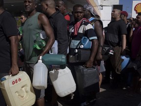 People hold empty containers as they wait to buy petrol at one of the few gas stations that are open and with fuel to sell in Rio de Janeiro, Brazil, Monday, May 28, 2018. A strike by truckers has caused shortages at gas stations and supermarkets across Latin America's biggest country.