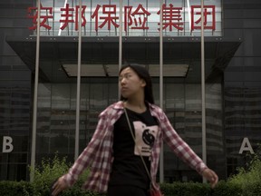 A woman walks past the offices of the Anbang Insurance Group in Beijing, Thursday, May 10, 2018. A court in Shanghai sentenced the founder of the Chinese insurance company that owns New York City's Waldorf Hotel to 18 years in prison on Thursday after he pleaded guilty to fraudulently raising billions of dollars from investors, state media reported.