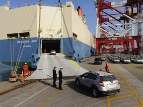 In this Jan. 14, 2015 photo, Chinese customs officials inspect cars being loaded for export at a port in Qingdao in eastern China's Shandong province. China said Thursday, May 24, 2018, that it will "firmly defend" its rights and interests against what it calls the Trump administration's abuse of national security provisions in trade. The Commerce Ministry's response came after the Trump administration launched an investigation into whether tariffs are needed on automobile imports on national security grounds. (Chinatopix via AP)
