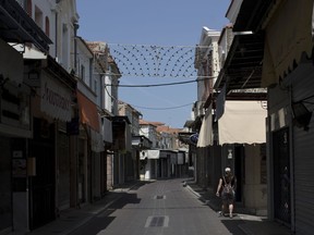 A woman walks on an empty street in the town of Mytilene on the northeastern Aegean island of Lesbos, Thursday, May 3, 2018. Stores and services have been closed on the island of Lesbos Thursday ahead of a visit by Prime Minister Alexis Tsipras in protest at the government and European Union migration policy which has left thousands of migrants and refugees stranded on the island.