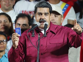 Venezuela's President Nicolas Maduro, holding a copy of the country's constitution, addresses supporters at the presidential palace in Caracas, Venezuela, after electoral officials declared he was re-elected on Sunday, May 20, 2018.