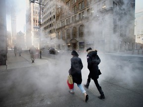 Pedestrians walk through mist from a grate at the corner of Temperance Street and Bay Street in Toronto. Las firm Wildeboer Dellelce will close off Temperance Street in downtown Toronto Thursday night to celebrate 25 years in business.