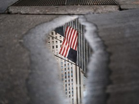 An American flag reflected in a puddle outside the New York Stock Exchange. As affluent baby boomers thank years of soaring markets for their paid-off mortgages and plump portfolios, millennials and the next cohort, Generation Z, are weighed down by student debt and stagnant wages.