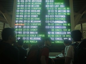 Passengers looks at an information board at Bali's international airport, Indonesia on Thursday, June 28, 2018, as airlines canceled flights. The Mount Agung volcano has shot ash 2,000 meters into the atmosphere, disrupting the travel plans of thousands as several airlines canceled flights from the Indonesian tourist island.