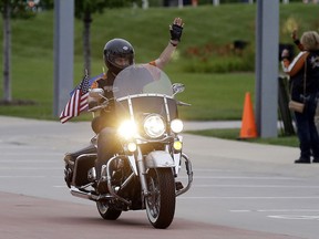 FILE - In this Aug. 2, 2013 file photo, Wisconsin Governor Scott Walker rides a Harley Davidson motorcycle to the motorcycle museum in Milwaukee. The Republican governor faces revved up criticism of the Milwaukee-based company from President Donald Trump. The president on Tuesday, June 26, 2018, tweeted that if Harley goes through with its plans to move some production overseas, "it will be the beginning of the end."