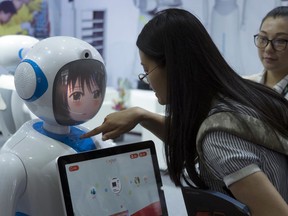 Women interact near a robot designed by Chinese robotics company Pangolin at the Consumer Electronics Show Asia 2018 in Shanghai, China on Friday, June 15, 2018. President Donald Trump is poised to hike the price of Chinese-made flat-screen TVs and ultrasound machines for American buyers. They are part of a tech imports worth up to $50 billion on which Trump is preparing to slap 25 percent tariffs in response to complaints Beijing steals or pressures foreign companies to hand over technology.