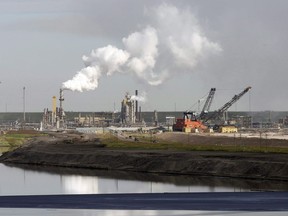 A tailings pond reflects the Syncrude oilsands mine facility near Fort McMurray, Alta., Wednesday, July 9, 2008. A production shutdown due to a power outage at Syncrude Canada's oilsands mine near Fort McMurray, Alta., is expected to free up pipeline space out of Western Canada and ease discounts on pricing for heavy oil.