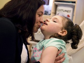 In this April 23, 2018, photo, Meagan Patrick kisses her daughter, Addelyn Patrick, 5, in the playroom at Realm of Caring in Colorado Springs, Colo. Addelyn was born with a brain malformation and suffers from multiple forms of seizures. The U.S. Food and Drug Administration is expected to decide soon whether to give its first approval to a prescription drug made from the marijuana plant. But parents, including Meagan, who have used other products containing chemicals from the plant to treat their children's severe forms of epilepsy are feeling more cautious than celebratory.