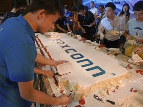 Workers cut a giant cake to celebrate Taiwan-based contract manufacturing giant Foxconn's 30th anniversary of its first investment in Shenzhen, south China's Guangdong province Wednesday, June 6, 2018. The head of Taiwan's Foxconn, which assembles Apple iPhones and other tech products, says Washington's dispute with China is over technology rather than trade.