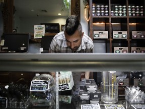FILE - In this June 27, 2017, file photo, Jerred Kiloh, owner of the Higher Path medical marijuana dispensary, stocks shelves with with cannabis products in Los Angeles. Several marijuana businesses in California warned Friday, June 29, 2018 that they could face steep financial losses unless the state extends a July 1 deadline imposing strict standards for pot testing and packaging.