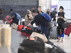 Travellers pick up their luggage at a baggage carousel at the Ottawa Airport.