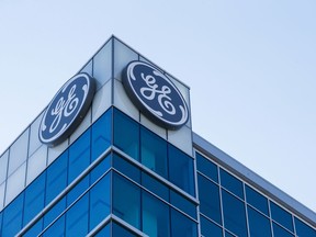 FILE- In this Jan. 16, 2018, file photo, the General Electric logo is displayed at the top of their Global Operations Center in the Banks development of downtown Cincinnati. A year after taking over an ailing American conglomerate, CEO John Flannery is calving off larger chunks of General Electric, spinning off its health care business and selling its stake in the oil services company, Baker Hughes.