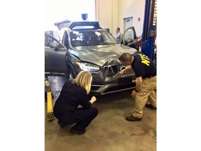 FILE - In this March 20, 2018 file photo provided by the National Transportation Safety Board, investigators examine a driverless Uber SUV that fatally struck a woman in Tempe, Ariz.  An Arizona police report says the human backup driver the Uber autonomous SUV was streaming a television show on Hulu just before the vehicle struck and killed a pedestrian in March. The Arizona Republic reported that the driver was watching "The Voice," a television musical talent show. The newspaper received the more than 300-page report from Tempe police on Thursday, June 21.  (National Transportation Safety Board via AP)