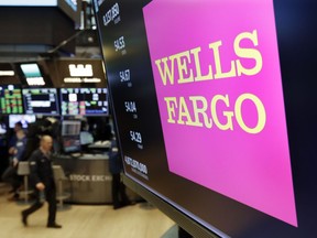 FILE - This May 17, 2018 file photo shows the Wells Fargo logo above a trading post on the floor of the New York Stock Exchange. Wells Fargo is selling more than 50 retail bank branches in Indiana, Michigan, Wisconsin and Ohio to a Flagstar Bancorp subsidiary.