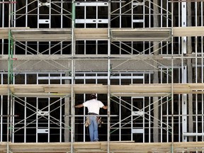 FILE- In this Friday, Oct. 6, 2017, file photo, a worker helps build an apartment and retail complex in Nashville, Tenn. The National Association for Business Economics says in its latest quarterly outlook that its panel of 45 economists expects the economy, as measured by the gross domestic product, to expand 2.8 percent this year. That is down slightly from the panel's March forecast which put GDP growth this year at 2.9 percent.