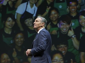 FILE - In this March 23, 2016, file photo, Starbucks CEO Howard Schultz walks in front of a photo of Starbucks baristas, at the coffee company's annual shareholders meeting in Seattle. Starbucks Corp. says Schultz is stepping down executive chairman later this month. Schultz, who oversaw the transformation of Starbucks into a global chain with more than 28,000 locations, had retired as CEO last year to focus on innovation and social impact projects as executive chairman.